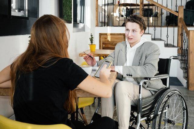 there-is-two-woman-in-office-and-discussing-something-one-on-wheelchair